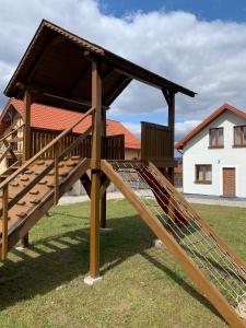 een houten speelplaats in een tuin met een gebouw bij Agroturystyka u Aleksa in Krajno-Zagórze