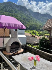 een tafel met een vaas met bloemen op een balkon met een oven bij Holiday Apartment in Swiss Alps in Gsteigwiler