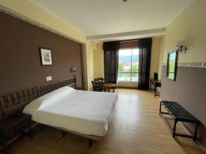 a bedroom with a bed and a table and a window at Hotel Eumesa in Puentedeume