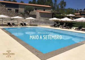 a swimming pool with chairs and umbrellas in front of a building at Quinta do Medronheiro Hotel Rural in Viseu