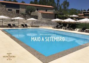 uma piscina com cadeiras e guarda-sóis em frente a um edifício em Quinta do Medronheiro Hotel Rural em Viseu