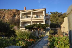 a building with a balcony and a garden with flowers at Liogerma in Agios Ioannis Kaspaka