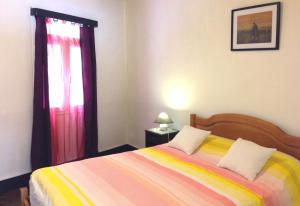 a bedroom with a bed with a colorful blanket and a window at Holidays Madeira in São Vicente