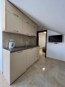 a kitchen with white cabinets and a tv on the wall at Venice Apartments in Tivat