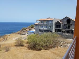 a house on the side of a hill next to the ocean at chez albino guest house in São Filipe