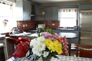 um vaso de flores sentado numa mesa numa cozinha em Seascape on the edge of town: 4 beds all ensuite. em Belmullet