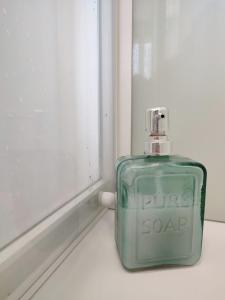 una botella de perfume verde sentada junto a una ventana en Charmant T1 bis dans un quartier calme en Brest