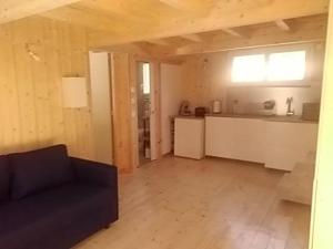 a living room with a black couch and a kitchen at Studio dans les pins Lacanau in Lacanau
