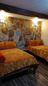 a room with two beds and a stone wall at Hotel Posada El Camino in Chignahuapan