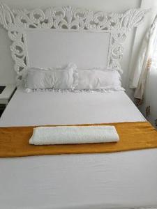 Una cama blanca con una tabla de madera. en Golden Nest en Mombasa