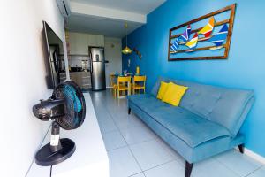 ein Wohnzimmer mit einer blauen Couch und einem Ventilator in der Unterkunft Muro Alto Condomínio Clube - FLAT TÉRREO in Porto De Galinhas