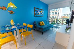 ein blaues Wohnzimmer mit einem Tisch und gelben Stühlen in der Unterkunft Muro Alto Condomínio Clube - FLAT TÉRREO in Porto De Galinhas