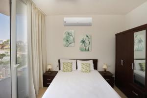 a bedroom with a white bed and a window at Prime Holidays Seashell in El Alamein