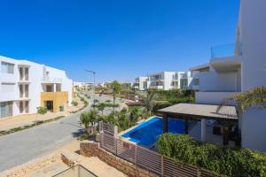 a building with a swimming pool next to a street at Prime Holidays Seashell in El Alamein