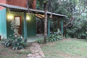 una casa verde con una porta nella foresta di sinharaja Aranuwa resort a Nelluwa