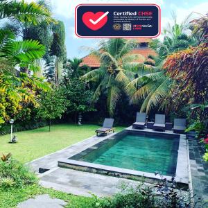 a swimming pool with two chairs in a garden at Pondok Naya - CHSE Certified in Ubud