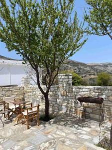 a patio with a tree and a table and a grill at Fabrica apartments in Apeiranthos