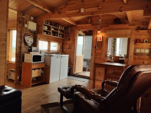 Sala de estar de una cabaña de madera con sofá y cocina en Cosy Cabin by Lake & Woods with Views, en Selfoss