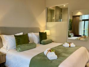 a bedroom with a large bed with towels on it at Menlyn Maine Residences - Kyoto king size xl bed in Pretoria