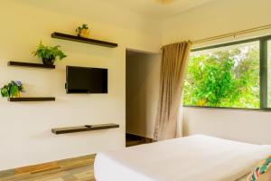 Habitación con cama, TV y ventana. en Mannoor Farms Mountain View Stays, Munnar, en Munnar