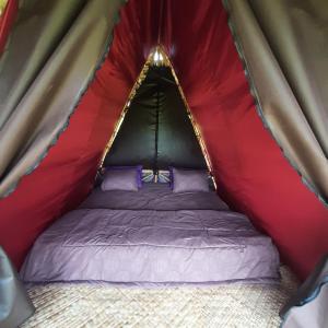 łóżko w czerwonym i zielonym namiocie w obiekcie Batan Nyuh Retreat w mieście Gianyar