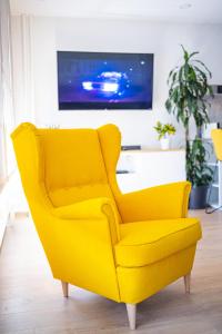 una sedia gialla in un soggiorno con TV di Dada's Cosy Condo a Zagabria