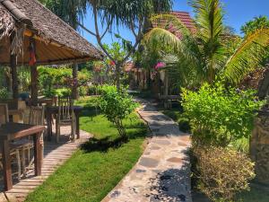 a garden with a table and chairs and a restaurant at Meno Dream Resort in Gili Meno