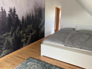 a bedroom with a bed and a painting of trees at Ferienwohnung am Plöner See in Ascheberg