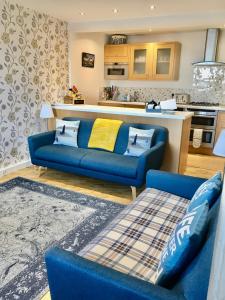 a living room with a blue couch and a kitchen at Harbour View 23 Shorehead in Stonehaven