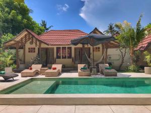 a house with a swimming pool with chairs and an umbrella at Meno Dream Resort in Gili Meno