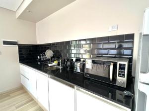 a kitchen with white cabinets and black tile on the wall at Tres Vientos - Lofts de Montaña Raco in Raco