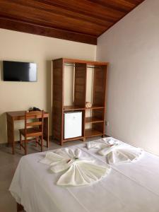 a bedroom with a bed with a desk and a television at Minas Hotel Unidade Centro in Mariana