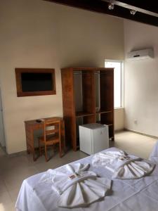 a bedroom with a bed and a desk and a tv at Minas Hotel Unidade Centro in Mariana