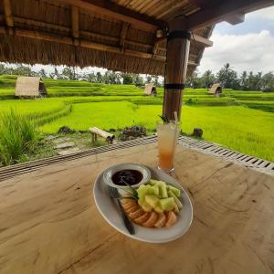 a plate of food on a table with a glass of juice at Batan Nyuh Retreat in Gianyar