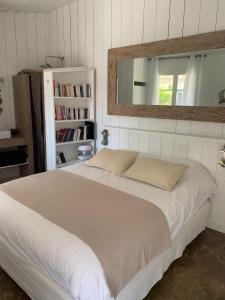 Schlafzimmer mit einem großen weißen Bett und einem Spiegel in der Unterkunft Beach Cottage in Le Bois-Plage-en-Ré