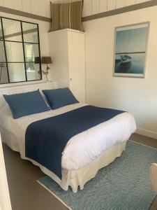 um quarto com uma cama grande com lençóis azuis e brancos em Beach Cottage em Le Bois-Plage-en-Ré