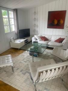 ein Wohnzimmer mit einem Sofa und einem Glastisch in der Unterkunft Beach Cottage in Le Bois-Plage-en-Ré