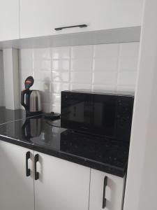 a kitchen with a microwave and a black counter top at 2-х комнатная квартира in Taraz