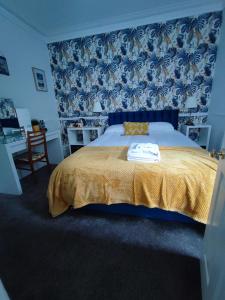 a bedroom with a bed with a yellow blanket and blue wallpaper at Score Valley Country House in Ilfracombe