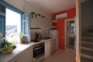 a kitchen with white cabinets and a large window at Villa Nefeli Tinos in Triandáros