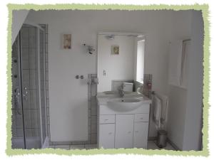 y baño blanco con lavabo y ducha. en Ferienwohnung zum Bernerhof en Lindenberg