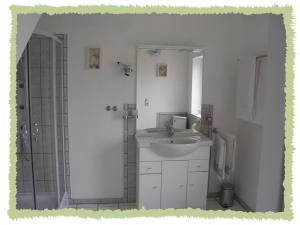 a white bathroom with a sink and a shower at Ferienwohnung zum Bernerhof in Lindenberg