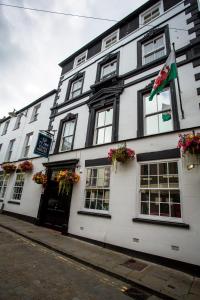 un bâtiment blanc avec un drapeau devant lui dans l'établissement Ty Dre Town House, à Caernarfon