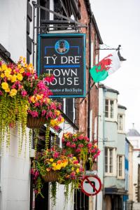 a sign for a thyme town house with flower baskets at Ty Dre Town House in Caernarfon