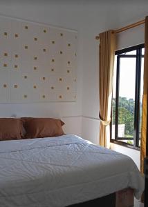 a bedroom with a bed with a window at RD Cottage Hills in Cihideung