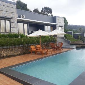 a house with a swimming pool with chairs and umbrellas at RD Cottage Hills in Cihideung