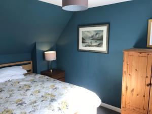 2 The Old Scout Hall في بليرغوري: غرفة نوم بحائط ازرق مع سرير وخزانة