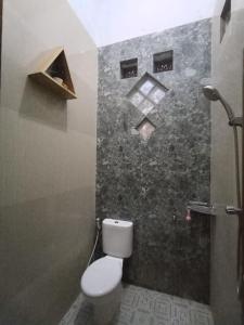 a bathroom with a toilet and a stone wall at Penginapan & Guest House Mbok Dhe Borobudur in Borobudur