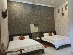 a bedroom with two beds and a mirror at Penginapan & Guest House Mbok Dhe Borobudur in Borobudur