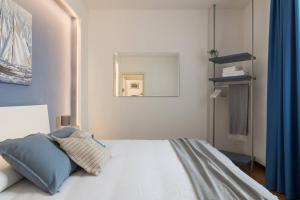a bedroom with a white bed with a blue curtain at Le 2 Perle 2.0 in Peschiera del Garda